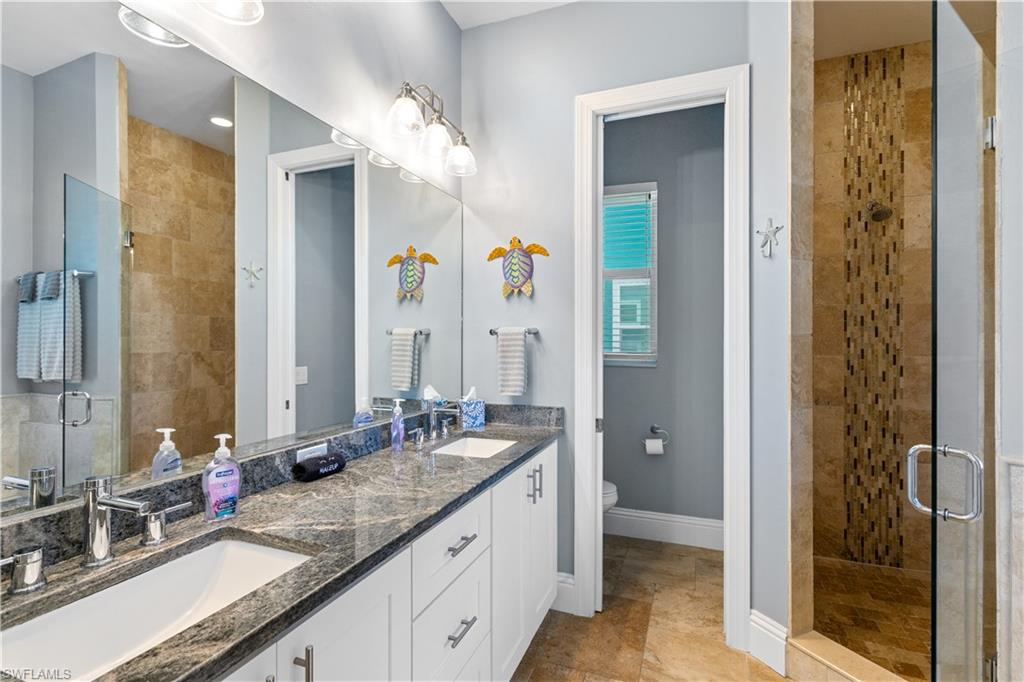 Bathroom featuring a dual vanity with granite countertops, undermount sinks, chrome faucets, separate water closet, walk in shower and full sized bathtub