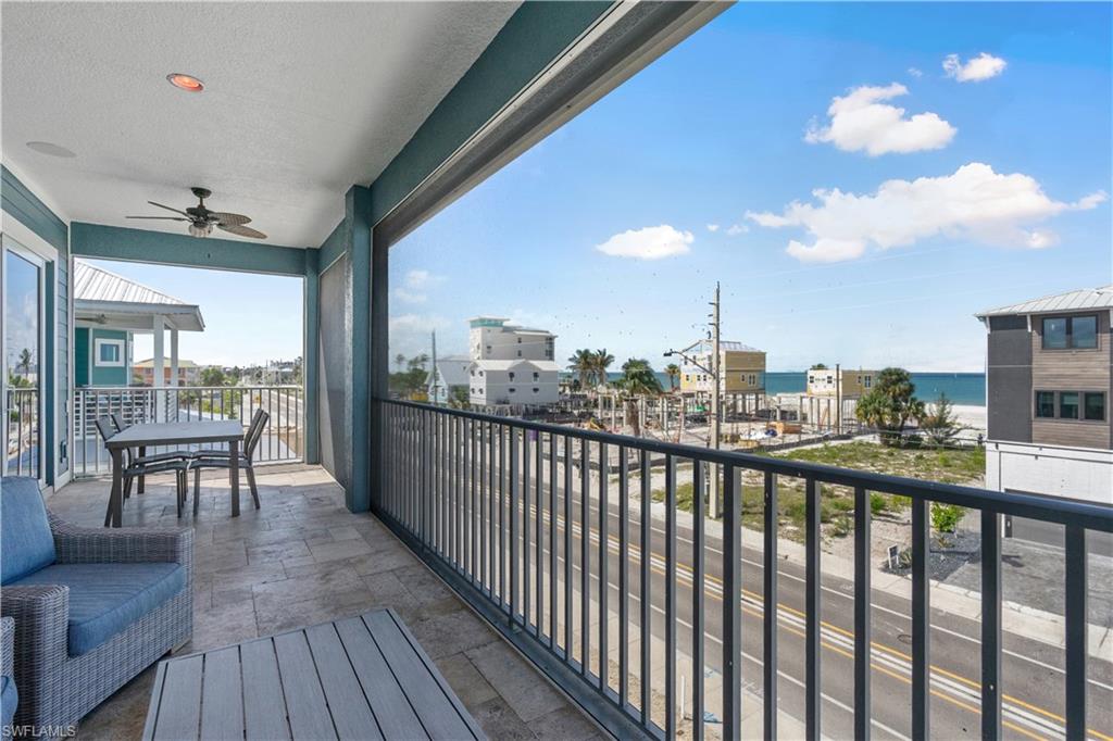 Spacious outdoor balcony with tile flooring, featuring a ceiling fan and recessed lighting