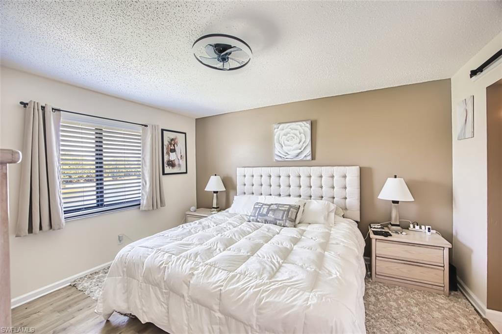 Bedroom featuring baseboards, a textured ceiling, and wood finished floors