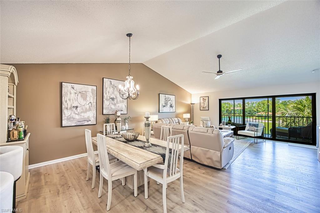 Dining room featuring lofted ceiling, light wood finished floors, a ceiling fan, a chandelier, and baseboards