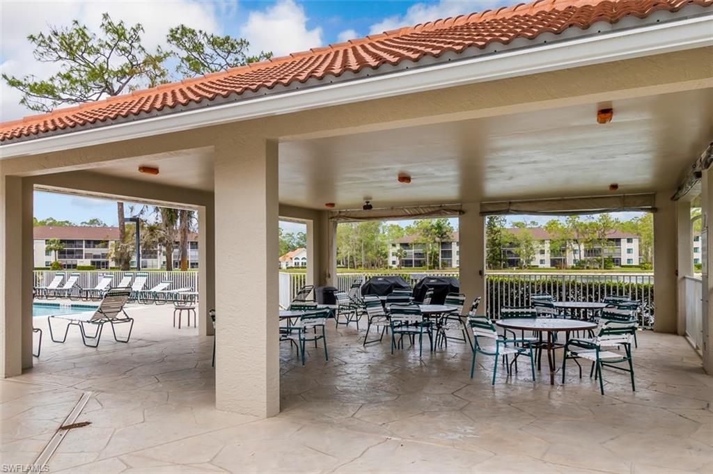 View of patio with fence, outdoor dining space, and a community pool