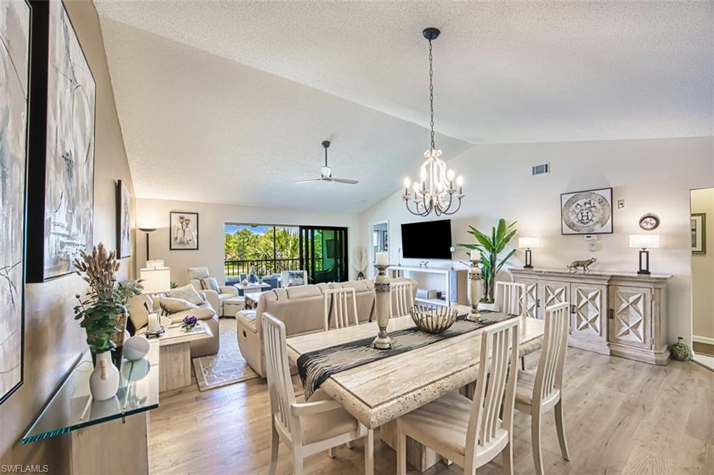 Dining space featuring lofted ceiling, a ceiling fan, light wood-style flooring, a chandelier, and baseboards
