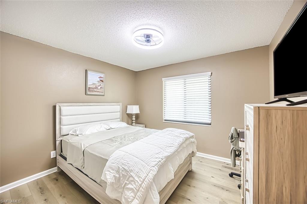 Bedroom with light wood-style floors, baseboards, and a textured ceiling
