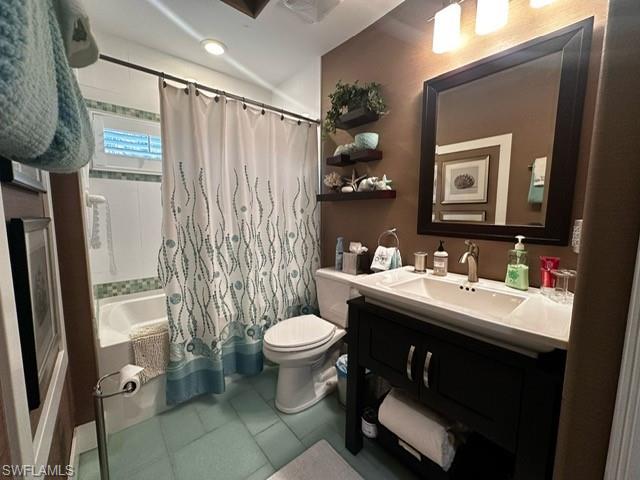 Bathroom with tile patterned floors, shower / bath combination with curtain, vanity, and toilet