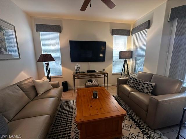 Living area featuring a ceiling fan, baseboards, and light tile patterned flooring