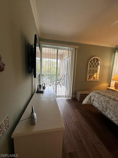 Bedroom with baseboards, wood finished floors, ornamental molding, and access to exterior