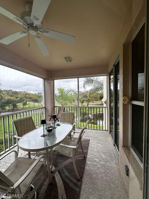 Sunroom / solarium with a ceiling fan and a water view
