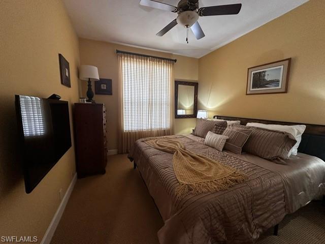 Carpeted bedroom with a ceiling fan and baseboards