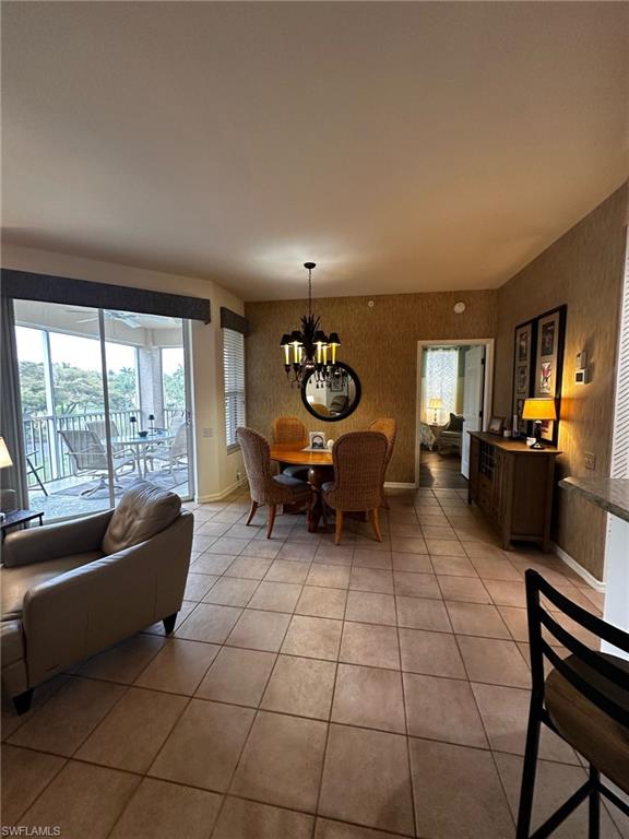 Dining room featuring baseboards, a notable chandelier, wallpapered walls, and light tile patterned flooring