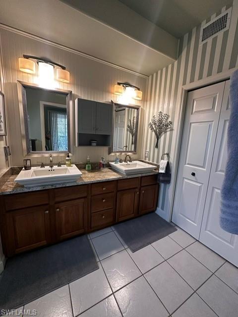 Bathroom featuring tile patterned floors, a sink, visible vents, and double vanity
