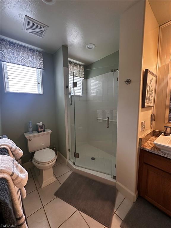 Bathroom featuring toilet, a stall shower, visible vents, tile patterned flooring, and vanity