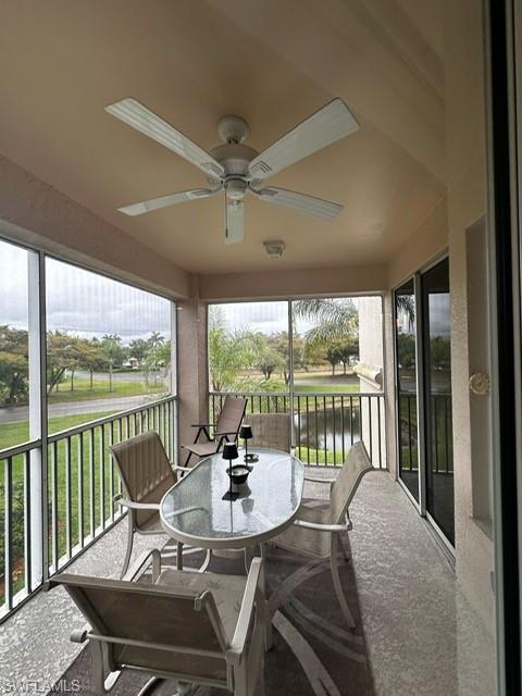 Sunroom with plenty of natural light, a ceiling fan, and a water view