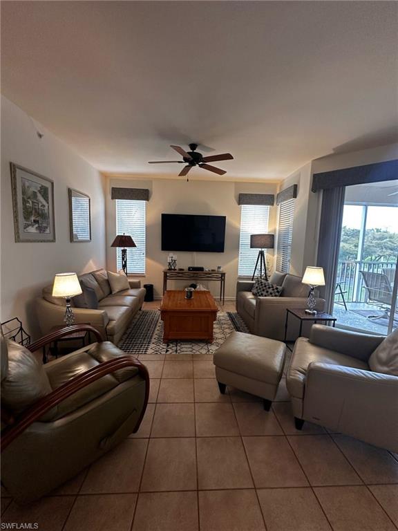 Living room with tile patterned floors, a wealth of natural light, and ceiling fan