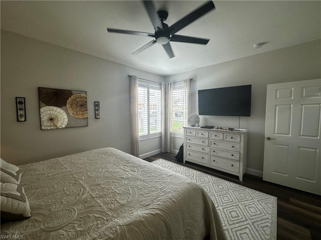 Bedroom with dark wood-style flooring, baseboards, and ceiling fan