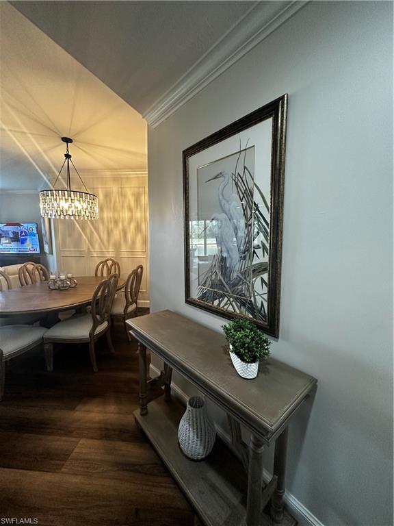 Dining space featuring crown molding, a notable chandelier, and dark wood-type flooring