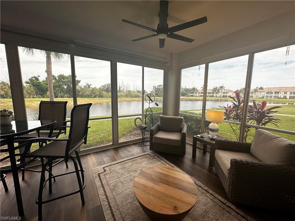 Sunroom with a water view, a ceiling fan, and wood finished floors