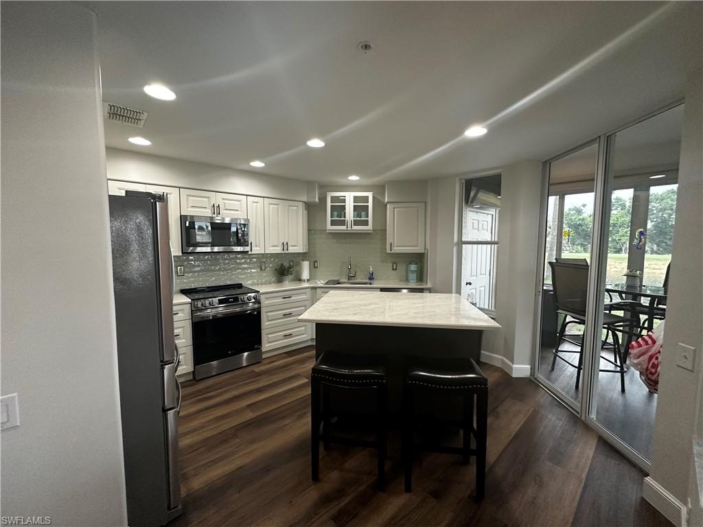 Kitchen featuring visible vents, a sink, baseboards, dark wood-style floors, and stainless steel appliances