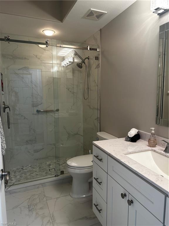 Bathroom with visible vents, vanity, marble finish floor, toilet, and a marble finish shower