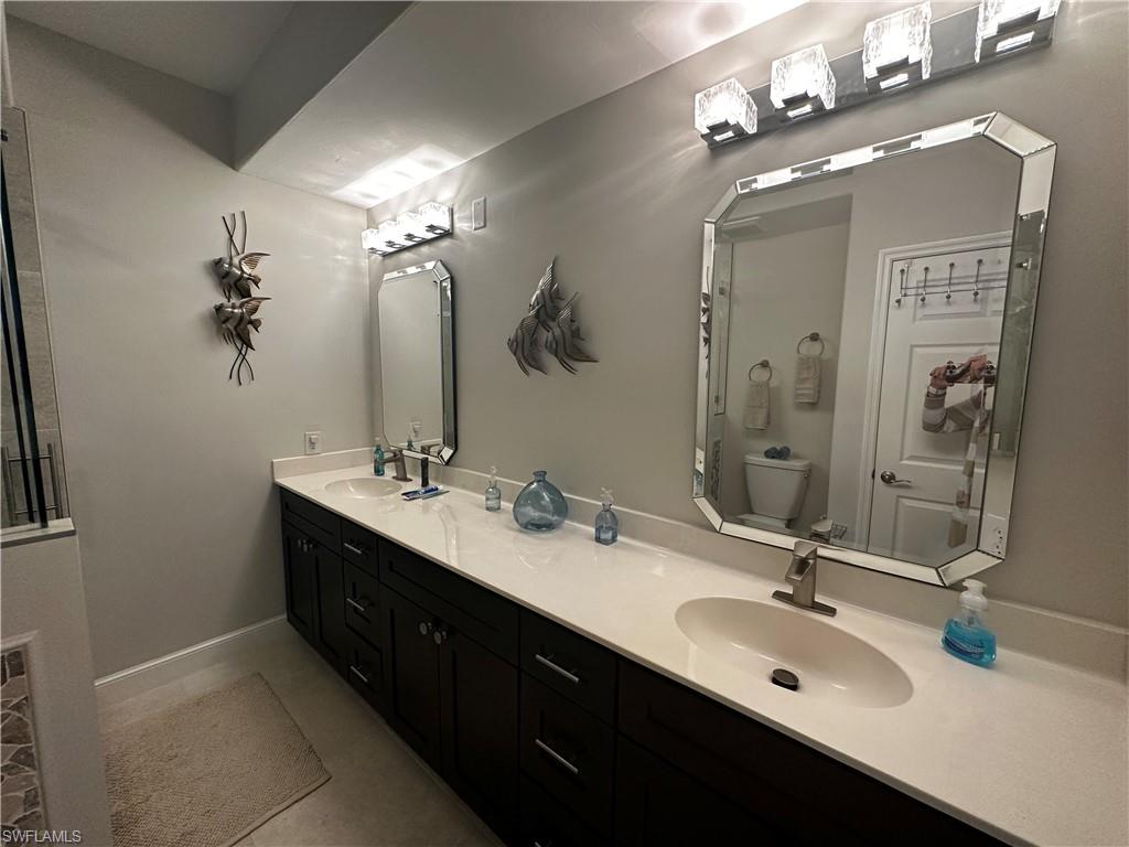 Full bathroom featuring double vanity, toilet, and a sink