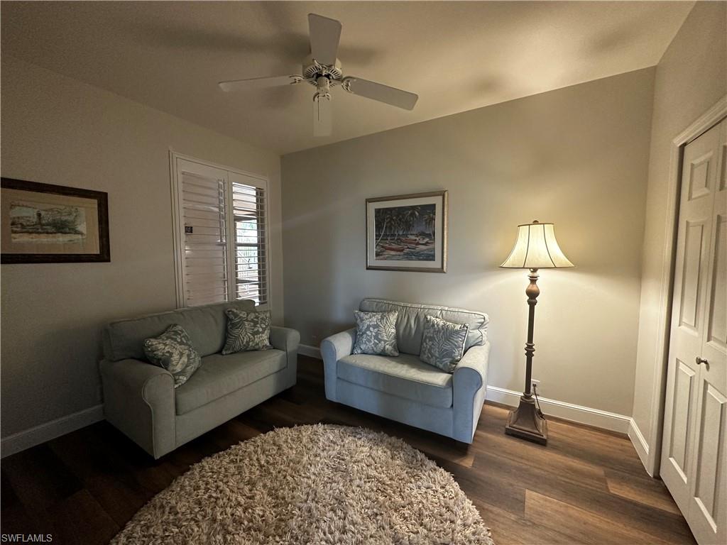 Living room featuring baseboards, dark wood-style floors, and ceiling fan