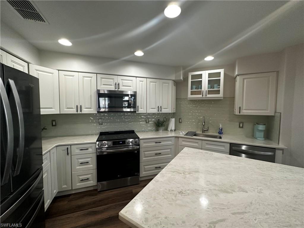 Kitchen featuring visible vents, a sink, white cabinets, and stainless steel appliances