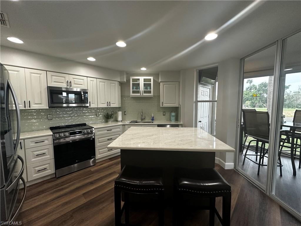 Kitchen with a sink, dark wood finished floors, appliances with stainless steel finishes, and backsplash
