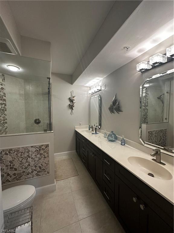 Full bath featuring a sink, double vanity, toilet, tile patterned floors, and tiled shower