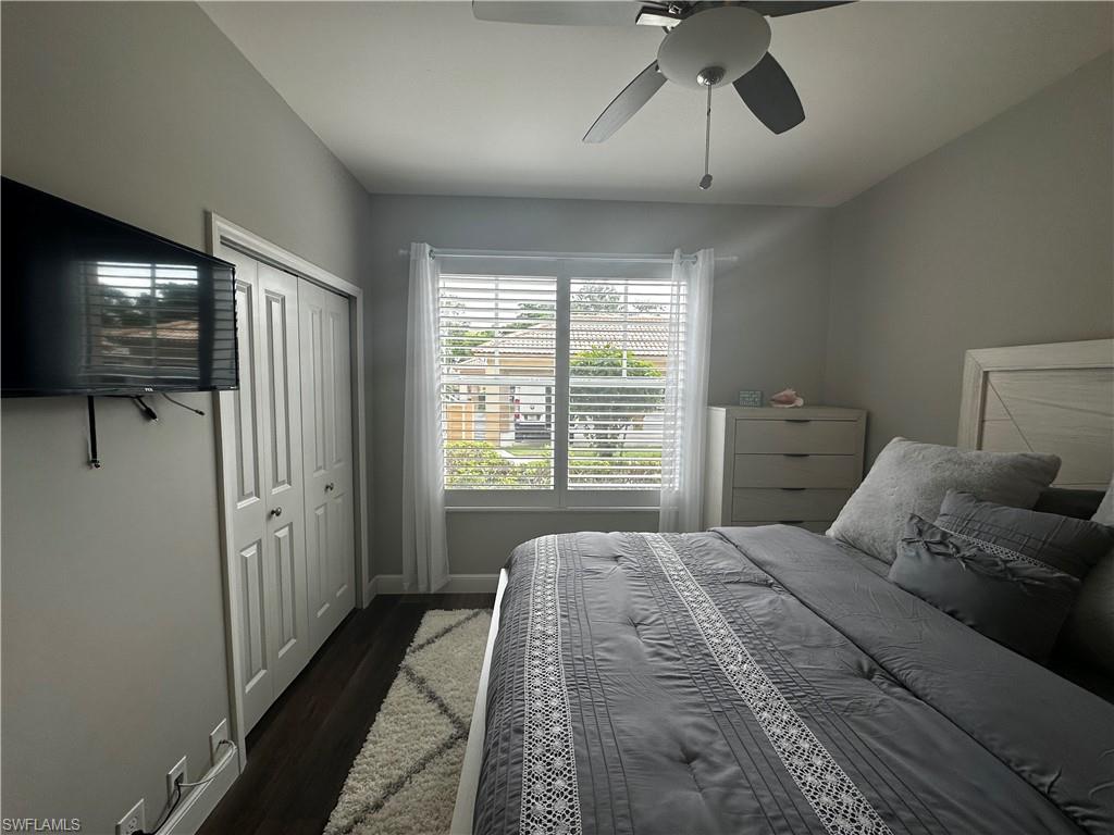 Bedroom with baseboards, ceiling fan, a closet, and dark wood-style flooring