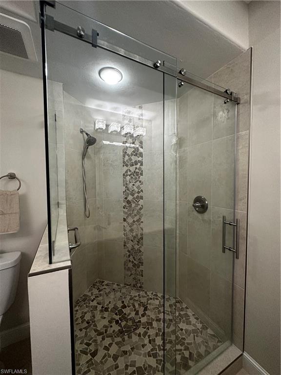 Full bath featuring toilet, visible vents, and a shower stall