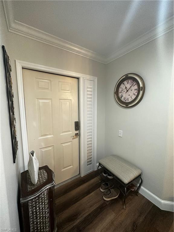 Doorway featuring baseboards, ornamental molding, and wood finished floors