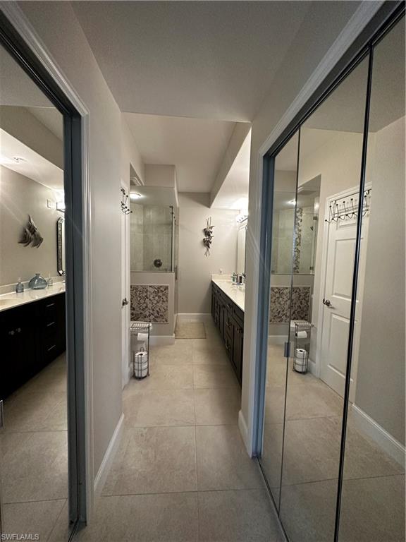 Bathroom with vanity, baseboards, walk in shower, and tile patterned floors
