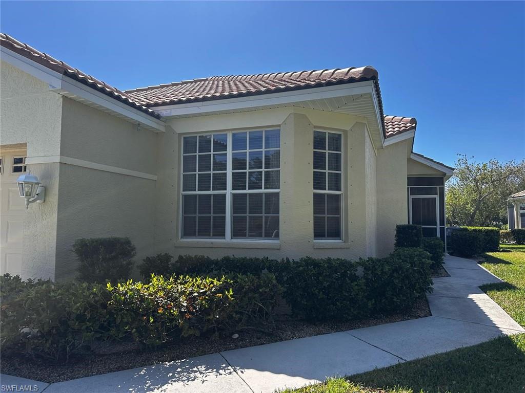 View of side of home with a tiled roof and stucco siding
