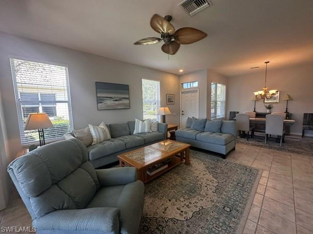 Living room featuring visible vents and ceiling fan with notable chandelier