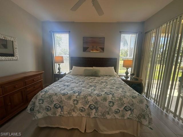 Bedroom with a ceiling fan, wood finished floors, and multiple windows