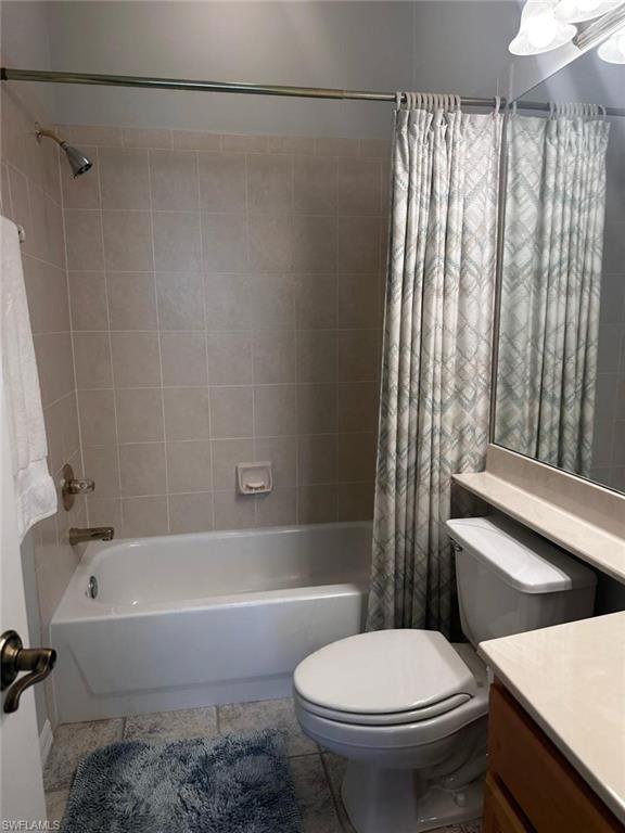 Full bathroom with tile patterned floors, shower / tub combo with curtain, vanity, and toilet