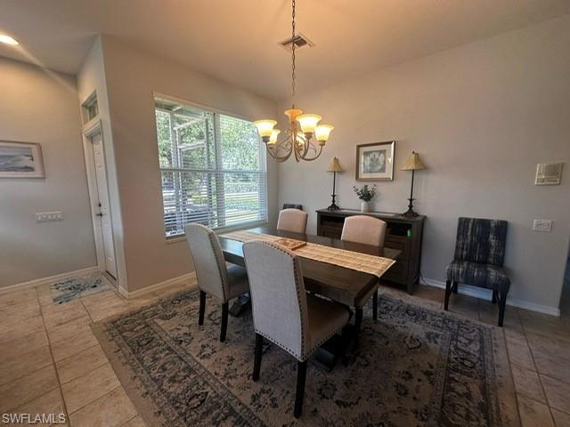 Tiled dining space featuring a chandelier, visible vents, and baseboards