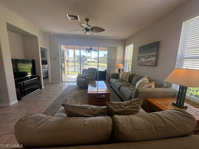 Living room with a wealth of natural light, a ceiling fan, visible vents, and baseboards