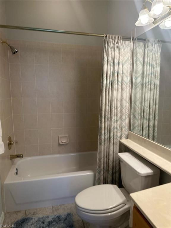 Bathroom featuring tile patterned flooring, toilet, vanity, and shower / bathtub combination with curtain