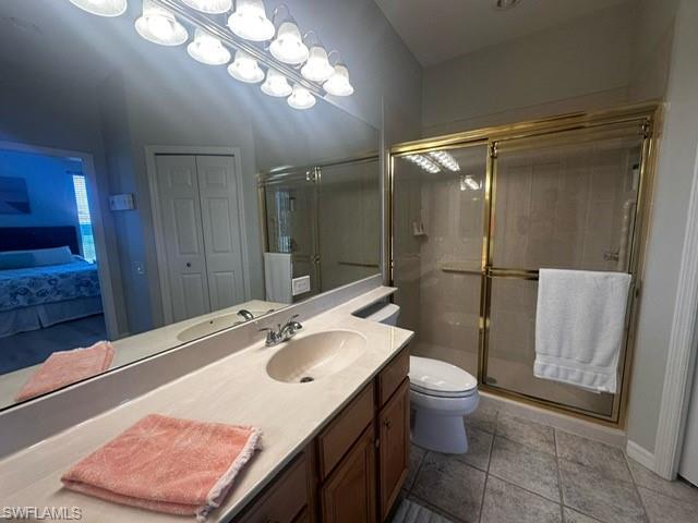 Full bath with toilet, vanity, tile patterned floors, and a stall shower