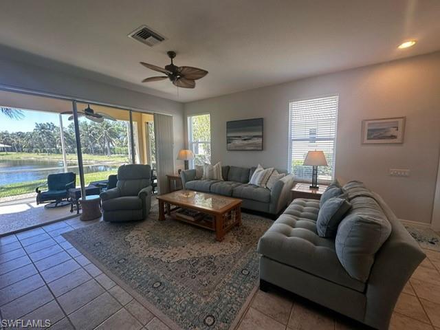 Living room with tile patterned floors, a water view, visible vents, recessed lighting, and a ceiling fan