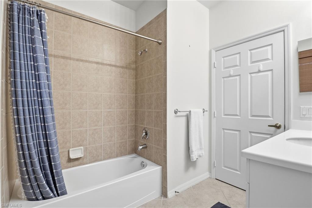 Full bathroom with light tile patterned floors, shower / bath combo, and vanity