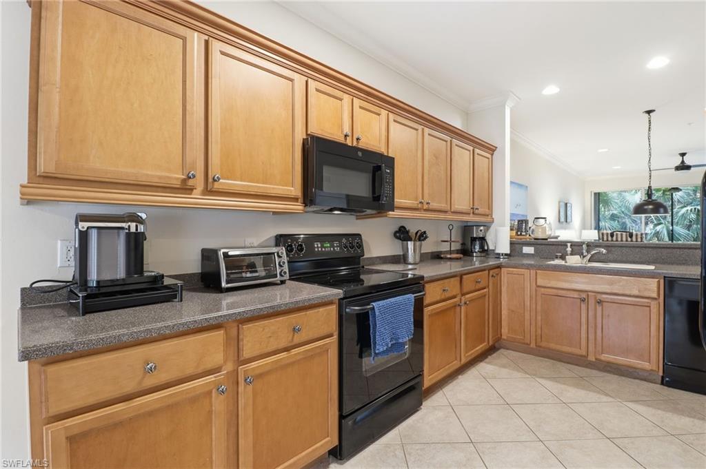 Kitchen with black appliances, ornamental molding, brown cabinetry, light tile patterned flooring, and pendant lighting