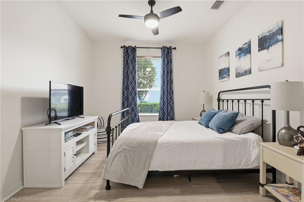 Den converted to a bedroom with light wood-type flooring and ceiling fan- Queen bed