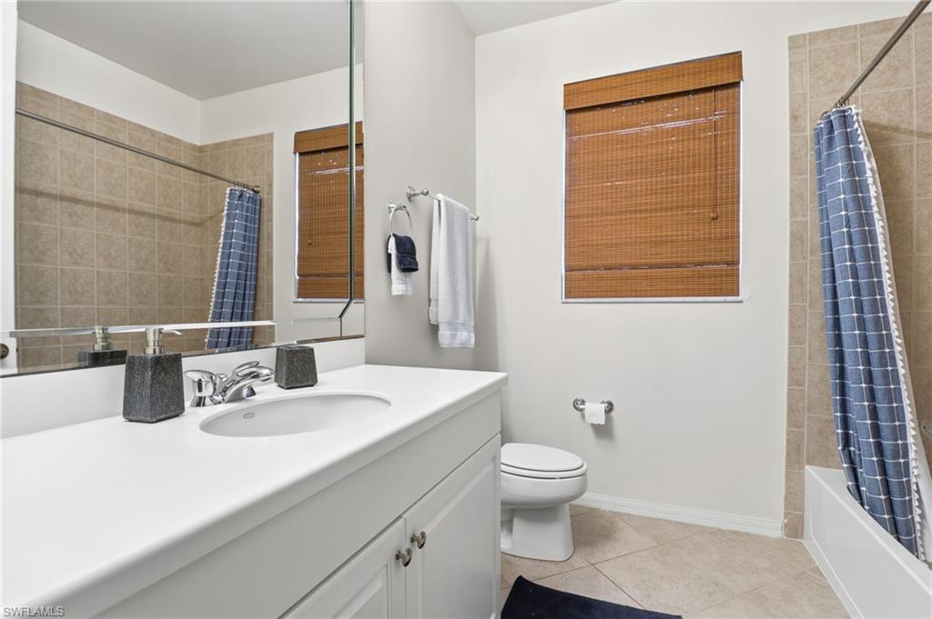 Full bath with light tile patterned flooring, vanity, and shower / tub combo with curtain