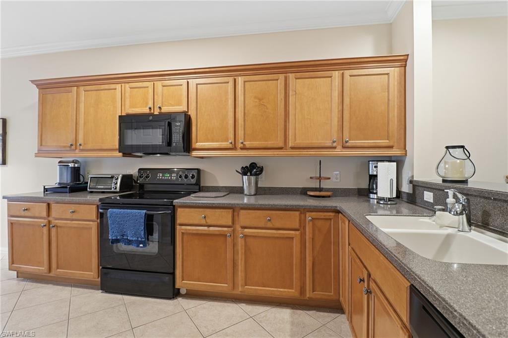 Kitchen featuring black appliances, crown molding, brown cabinets, and light tile patterned floors