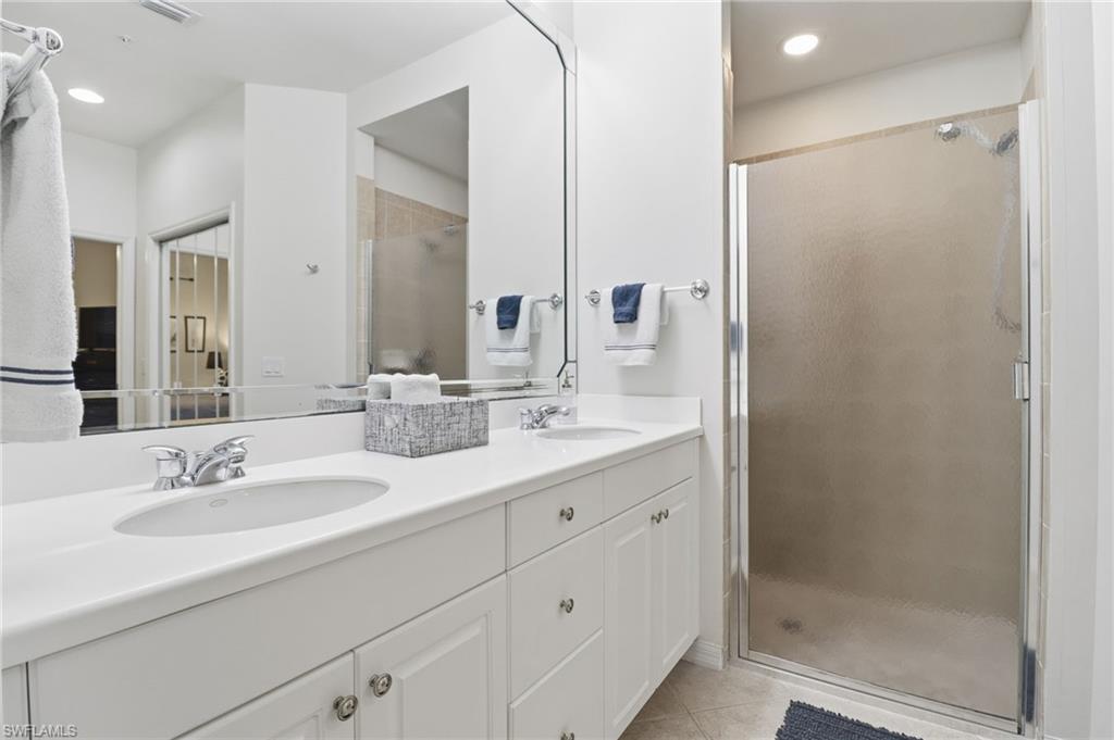Primary Bathroom featuring double vanity, a stall shower, light tile patterned flooring, and recessed lighting