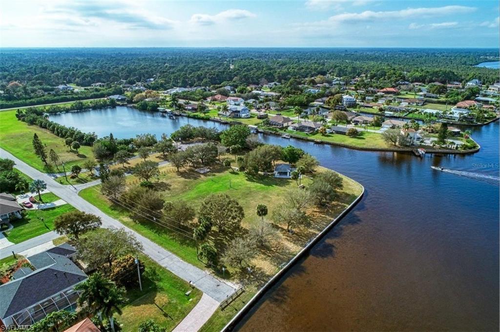 Expansive waterfront property featuring direct canal frontage, mature trees, and proximity to a freshwater lake