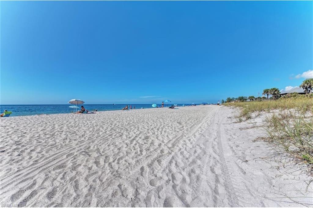 Expansive sandy beach with a clear blue sky and calm ocean waters