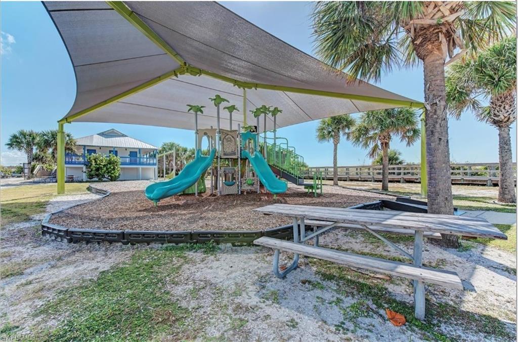 Playground area featuring a multi-level play structure with slides, a shade canopy, and a picnic table