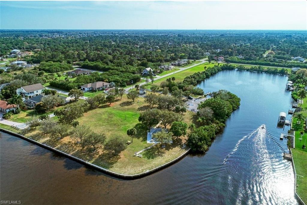 Waterfront property featuring a large grassy lot, mature trees, and direct water access